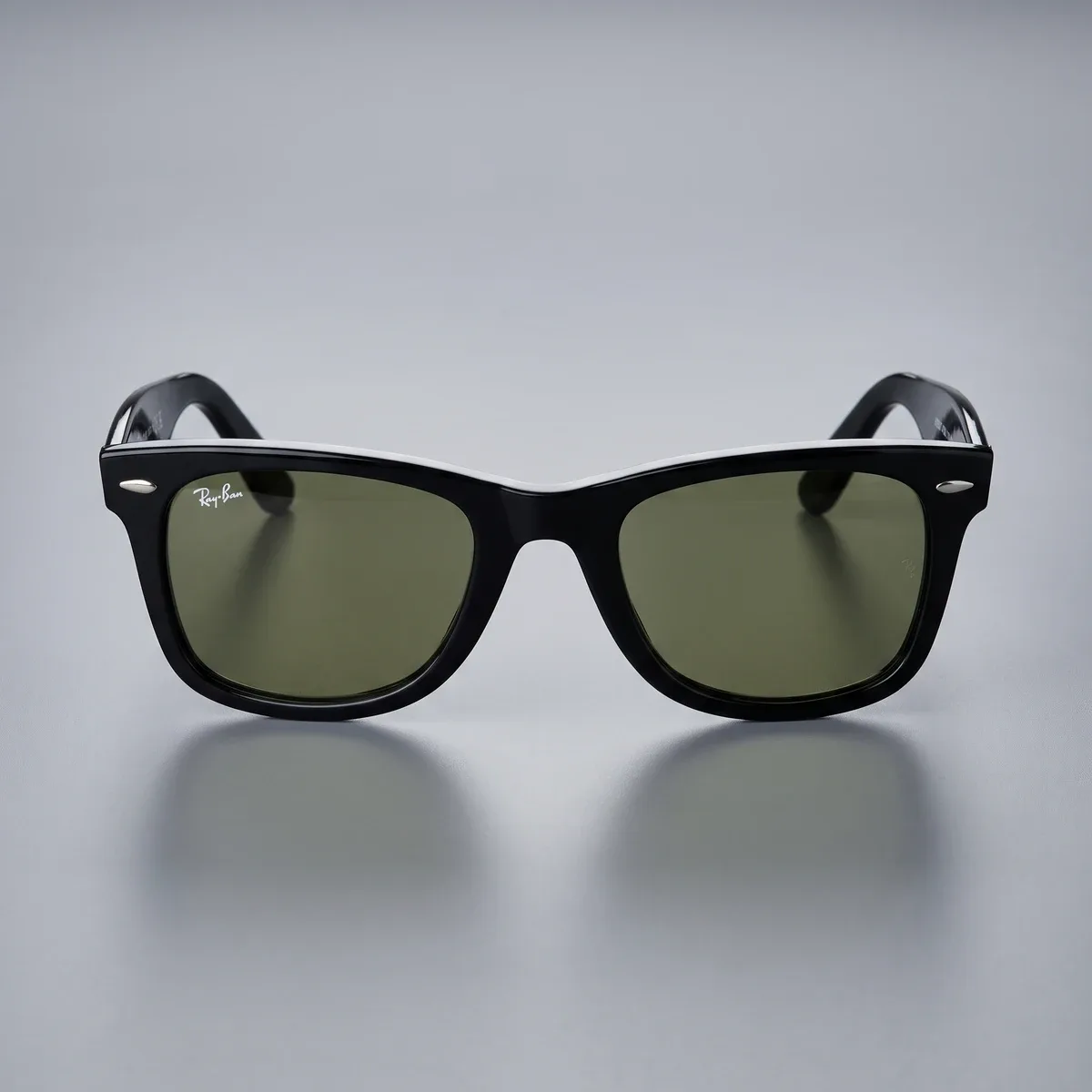 Front-facing dark sunglasses with olive-toned lenses on a softly lit grey surface.